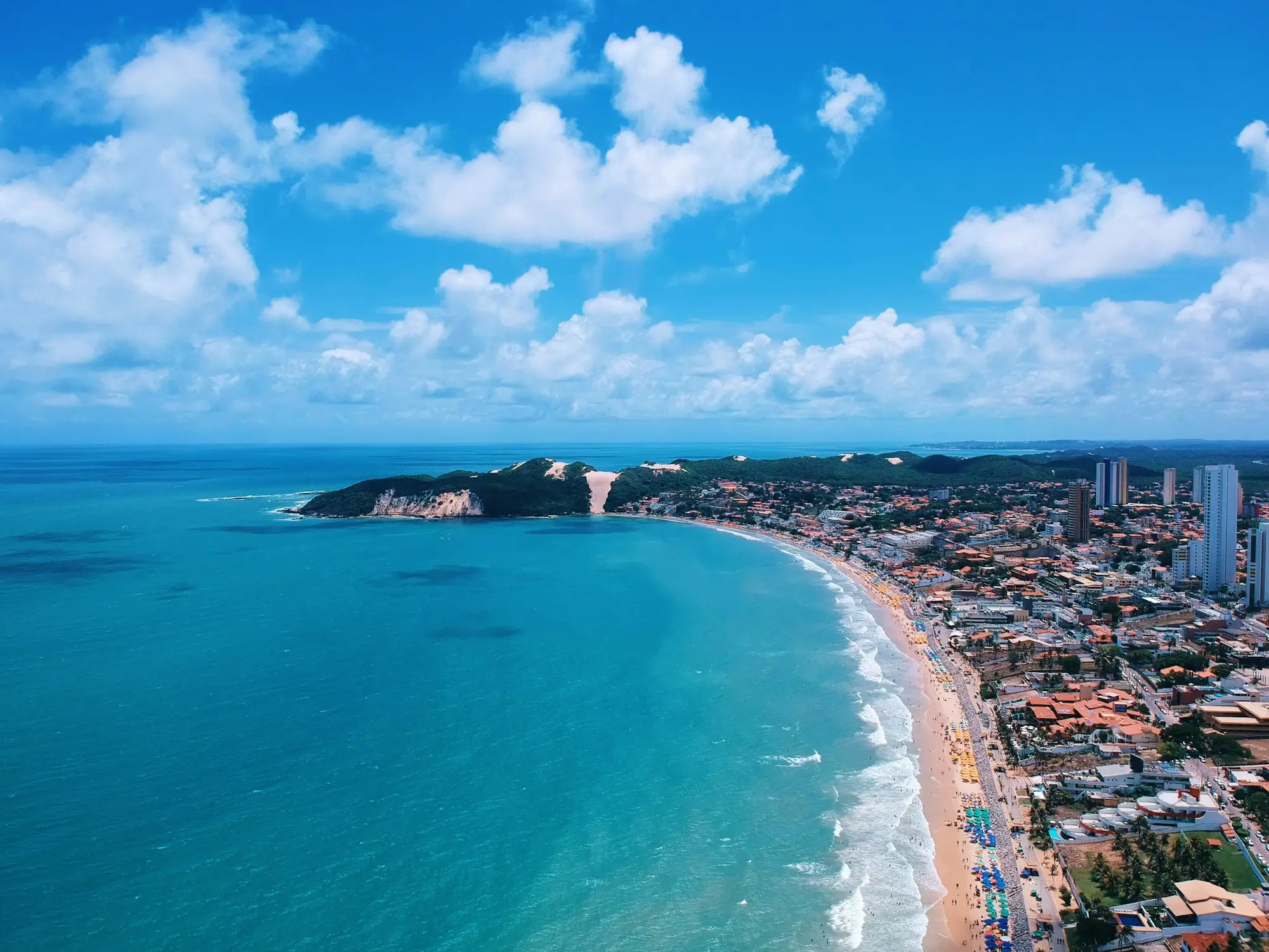 Vista aérea da orla com falésias e prédios à beira-mar na Paraíba